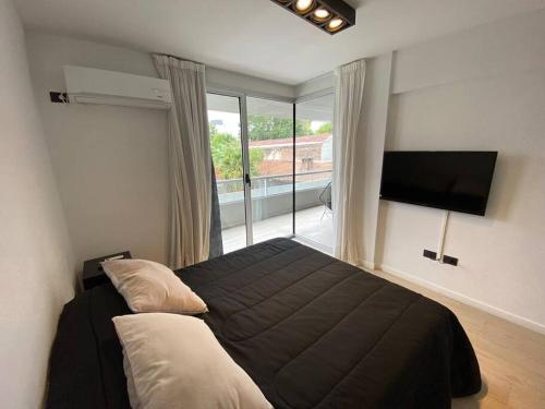 a bedroom with a bed and a large window at Departamento céntrico a estrenar - Con piscina y parking incluido in Tigre