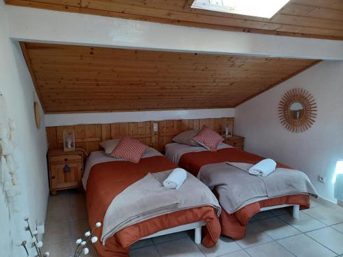 Duas camas num quarto com tectos em madeira em STUDIO LE MONT-CENIS, GARAGE pour motards et cyclistes, gare a 800m em Fourneaux