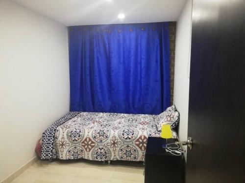 1 dormitorio con 1 cama con cortina azul en Funza Apartamento Normandia del Parque II, en Funza