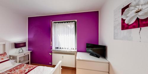 a bedroom with purple walls and a desk with a computer at Ferienwohnung Seeblick in Schalkenmehren