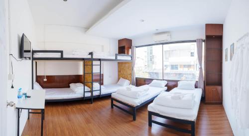 Pokój z łóżkiem piętrowym, kanapą i stołami w obiekcie Lamoon Hostel w mieście Hat Yai