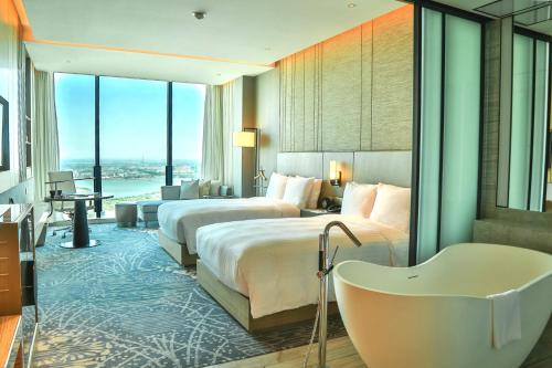 蘇州市にあるルネッサンス スーチョウ ウージャン ホテル ア マリオット ラグジュアリー＆ライフスタイル ホテルのベッド2台とバスタブ付きのホテルルームです。