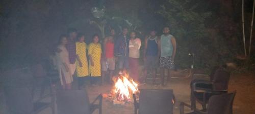 a group of people standing around a fire at Green Land Estate Homestay 5 Rooms With Garden View in Madikeri