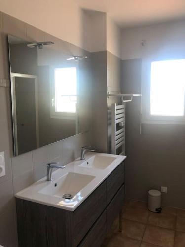 une salle de bain avec un lavabo et un grand miroir dans l'établissement Les Ecrehous de Saint Jean, à Barneville-Plage