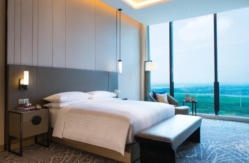 a bedroom with a large bed and large windows at Renaissance Suzhou Wujiang Hotel in Suzhou
