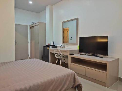 曼谷的住宿－HADA House Service Apartment，一间卧室配有一张床和一张书桌及电视