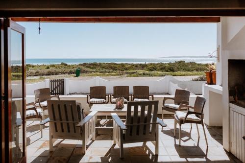 a patio with a table and chairs and a view of the ocean at Moschel in Paternoster