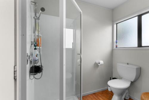 uma casa de banho com um WC e uma cabina de duche em vidro. em Simply Fabulous - Mangawhai Heads Holiday Home em Mangawhai