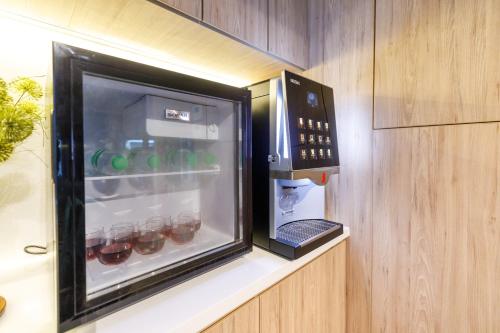 a refrigerator with drinks in it sitting on a shelf at Benjarong Hotel Bangkok in Ban Zong Katiam