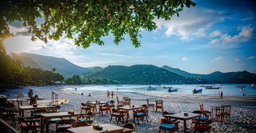 a beach with tables and chairs and people in the water at Havana Beach Resort Phangan in Thong Nai Pan Yai