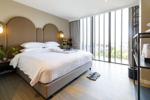 a bedroom with a large bed and large windows at Benjarong Hotel Bangkok in Ban Zong Katiam