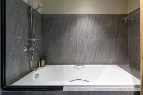 a bath tub in a bathroom with a shower at Benjarong Hotel Bangkok in Ban Zong Katiam