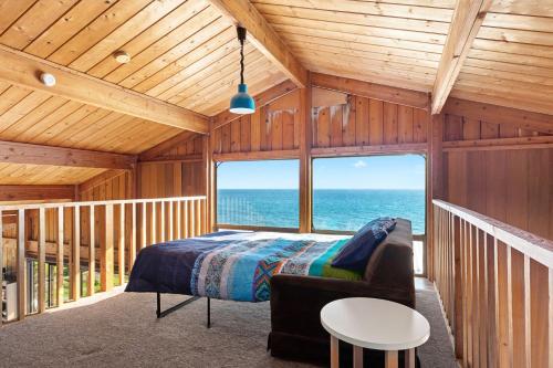 a bedroom with a bed and a view of the ocean at Cliffs End Beach Shack 105 Gold Coast Drive in Carrickalinga