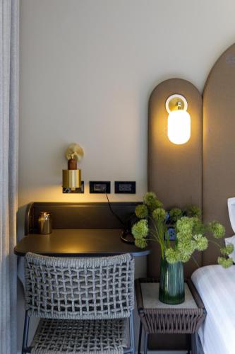 a bedroom with a bed and a table with a vase of flowers at Benjarong Hotel Bangkok in Ban Zong Katiam