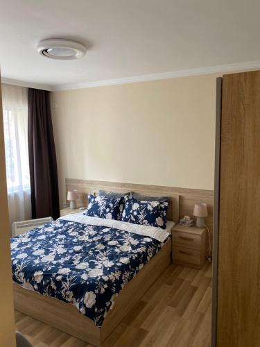 um quarto com uma cama com uma colcha floral azul em Luxury family apartament em Burgas
