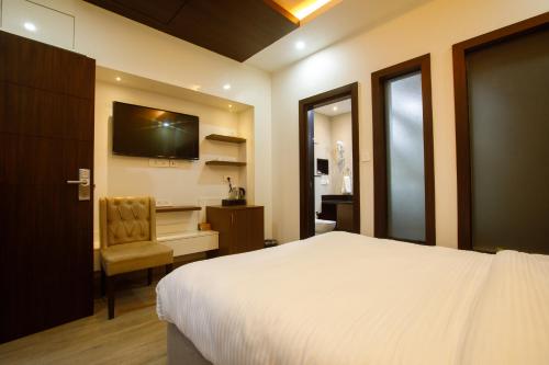 Sangam City Hotel Pure Veg في كاتماندو: غرفة نوم بسرير وكرسي وتلفزيون