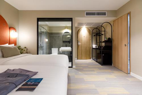 a bedroom with a white bed and a bathroom at Benjarong Hotel Bangkok in Ban Zong Katiam