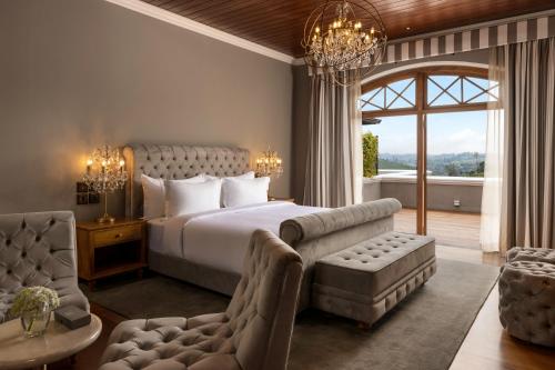 a bedroom with a bed and a couch and a chair at The Bellwood Manor in Nuwara Eliya