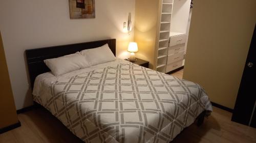 1 dormitorio con 1 cama y mesita de noche con lámpara en Departamento 2B en Condominio La Victoria, en Cuenca