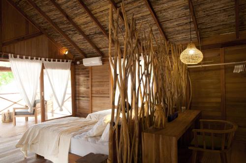 a bedroom with a bed and a table and a chandelier at Metita Beach & Dive Resort in Doruba