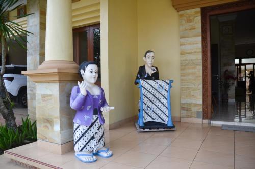 two statues of a woman standing next to a building at Roemah Canting Homestay in Yogyakarta