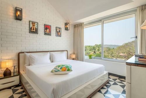 1 dormitorio con 1 cama blanca grande y ventana en 2Bed Stylish Home w Rooftop Pool nr Candolim Beach, en Nerul
