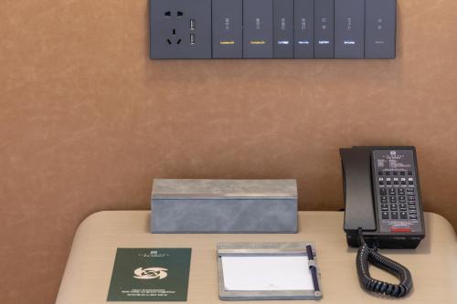 a desk with a telephone and a box on it at Guangzhou Baiyun Airport MeHood Liz Hotel Free Shuttle Bus to Canton Fair and to Airport in Guangzhou