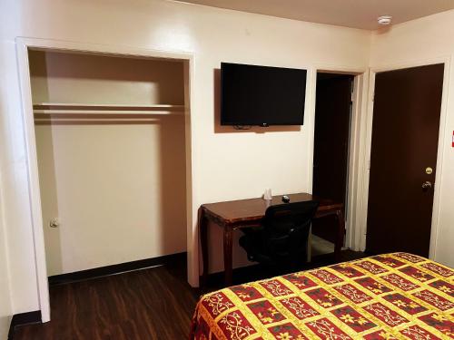 una camera d'albergo con letto, scrivania e TV di Lido Hotel a Huntington Park