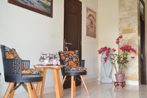 a dining room with two chairs and a table with flowers at Roemah Canting Homestay in Yogyakarta