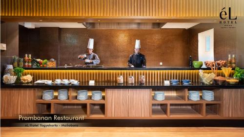 two chefs standing behind a counter in a restaurant at eL Hotel Yogyakarta Malioboro in Yogyakarta