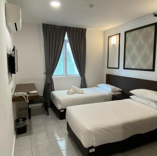 Kampong MortenにあるCapital O 90756 Cara Hulu Hotelのベッド2台と窓が備わるホテルルームです。