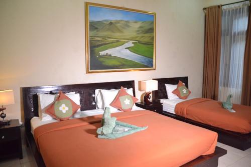 2 camas en una habitación de hotel con sábanas de color naranja en Roemah Canting Homestay, en Yogyakarta