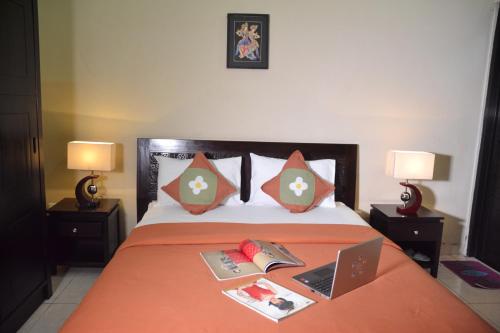 a bed with a laptop and books on it at Roemah Canting Homestay in Yogyakarta