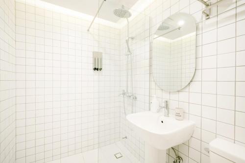 a white tiled bathroom with a sink and a mirror at Y Collection by Unboundi Gyeongju in Gyeongju