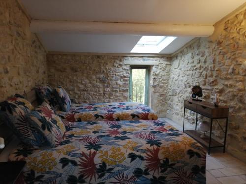 a bedroom with a bed in a stone wall at Gîte de l ancienne Poste in Bourdic