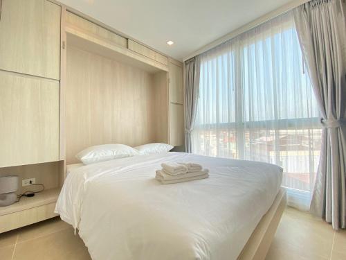 ein Schlafzimmer mit einem weißen Bett mit zwei Handtüchern darauf in der Unterkunft Olympus city garden by jack in Pattaya South