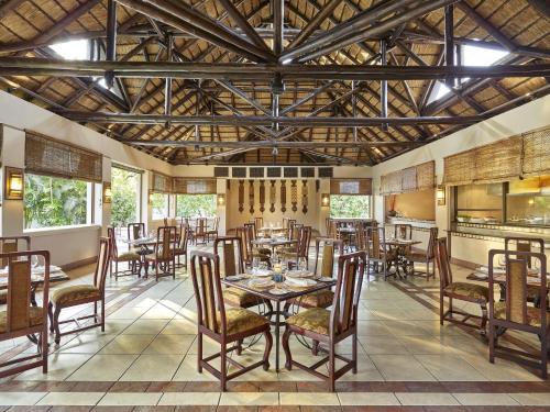 een eetkamer met tafels en stoelen en een plafond bij Taj Pamodzi Lusaka in Lusaka