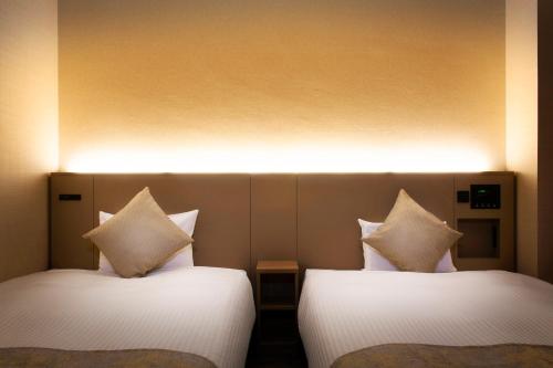 two beds sitting next to each other in a room at Hotel Villa Fontaine Tokyo-Kayabacho in Tokyo