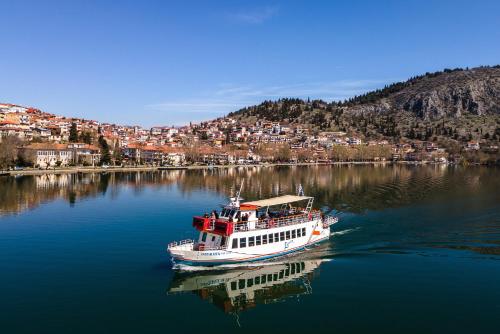 a boat on a river with a city in the background at Αρχοντικό Κίτσου - BOUTIQUE HOTEL in Kastoria