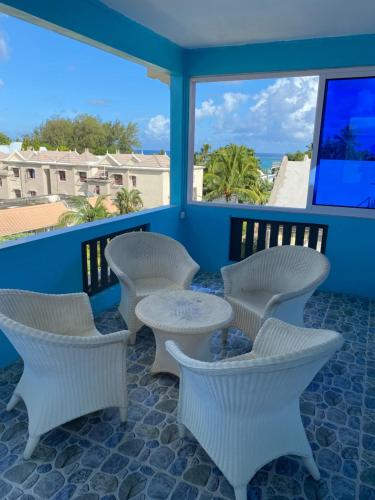 a patio with white chairs and a table on a balcony at Residence La Colombe in Grand Baie