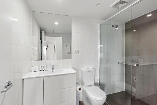 a white bathroom with a toilet and a shower at Quest Kelvin Grove in Brisbane