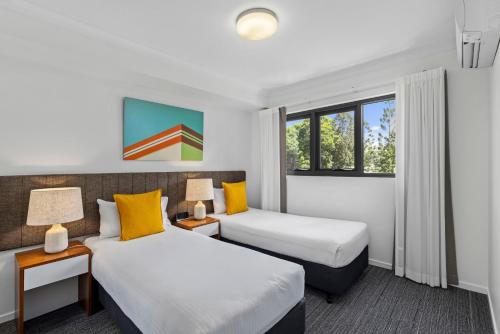 a hotel room with two beds and two lamps at Quest Kelvin Grove in Brisbane