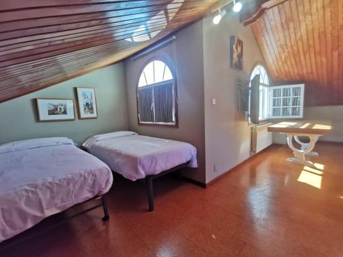 a bedroom with two beds and a desk and two windows at Monteferro, Nigrán, chalet con finca in Nigrán
