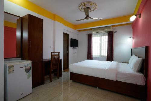 a bedroom with a bed and a desk and a refrigerator at Hotel Signature Cochin in Cochin