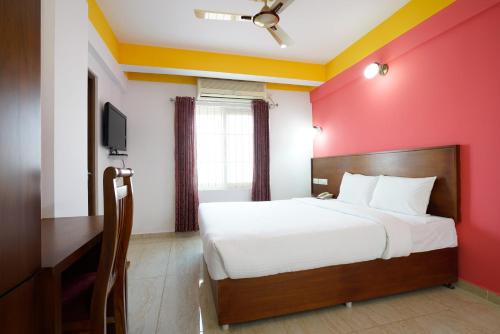 a bedroom with a bed and a red wall at Hotel Signature Cochin in Cochin