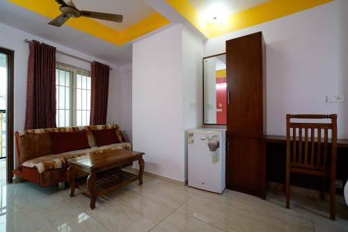 a living room with a couch and a table and a refrigerator at Hotel Signature Cochin in Cochin