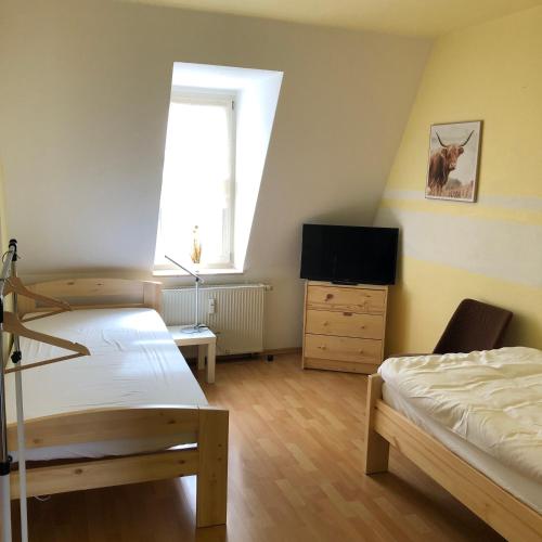um quarto com 2 camas, uma televisão e uma janela em Ferienwohnung Hohe Str. em Bernburg
