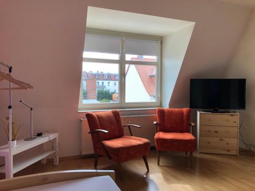 uma sala de estar com duas cadeiras e uma televisão em Ferienwohnung Hohe Str. em Bernburg