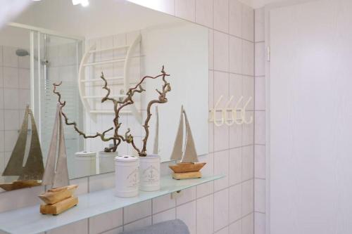 a bathroom with a shelf with vases and a mirror at Ferienwohnung Strandaster in Spieka-Neufeld