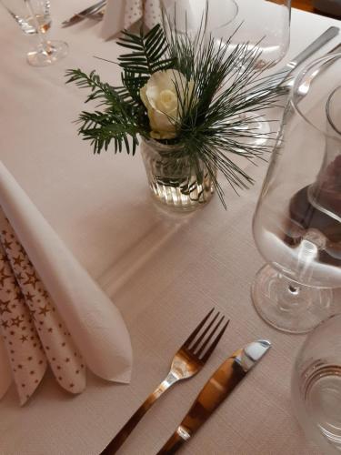 a table with a white table cloth with a vase with a plant at Gästezimmer Klinger-Tongisch in Apetlon
